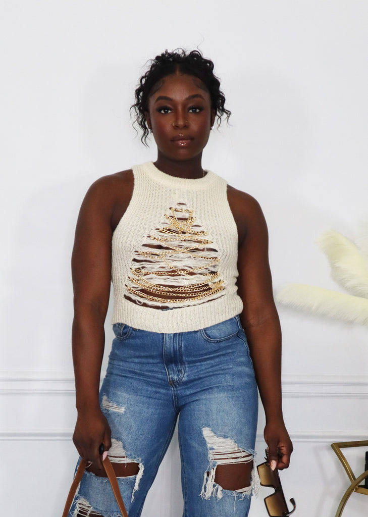 woman in a knit gold chain top wearing jeans 